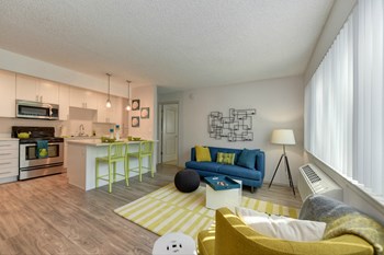 Living Room with View of Kitchen Living Room with Hardwood Inspired Floors, Yellow/White Rug, Large Window with Blinds, Blue Sofa and View of Kitchen - Photo Gallery 2