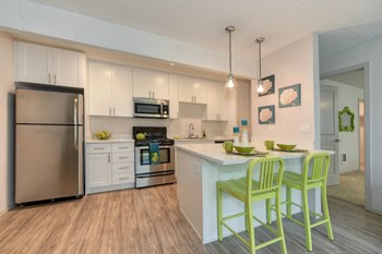 Kitchen with Hardwood Inspired Floors Kitchen with Hardwood Inspired Floors, Green Chairs, Refrigerator, White Cabinets and Small White Flower Paintings - Photo Gallery 5