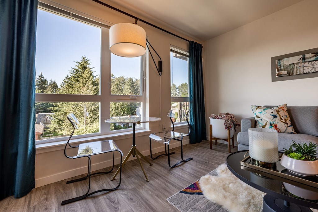 Model home living room with seating and large windows. 