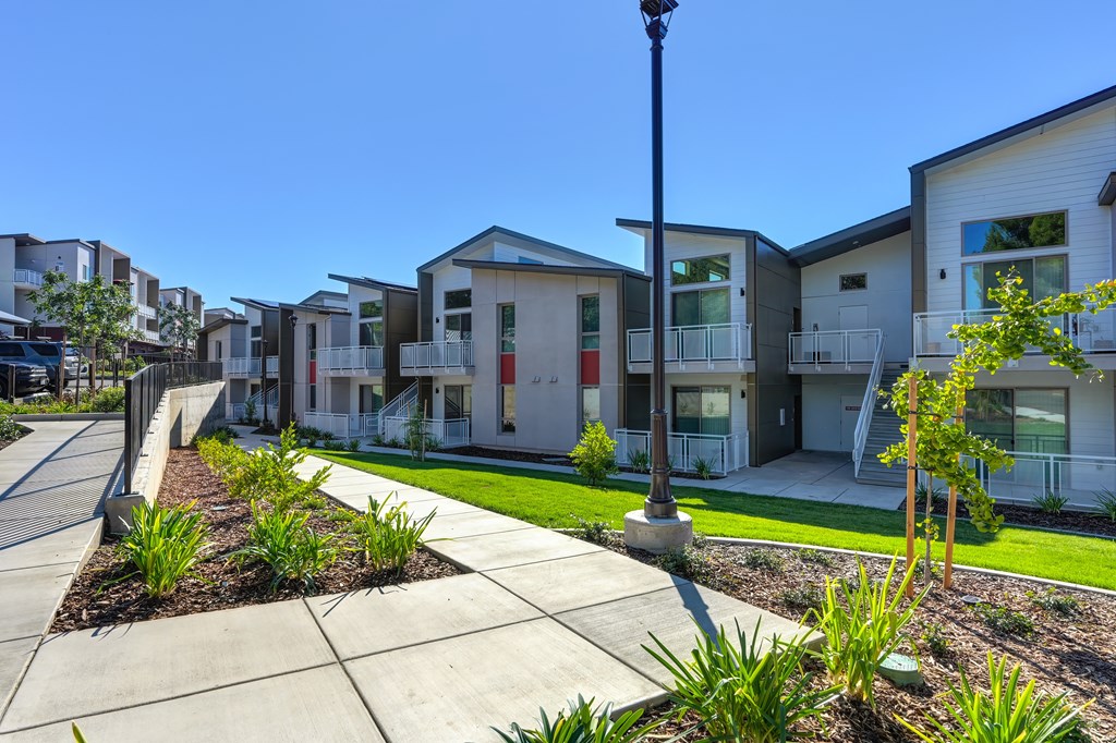 A row of modern houses with a sidewalk in front.