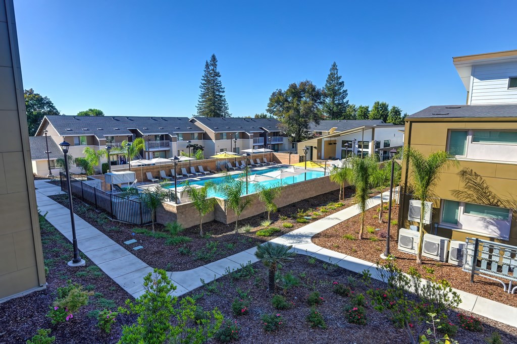 A pool surrounded by a fence and trees in a residential area.