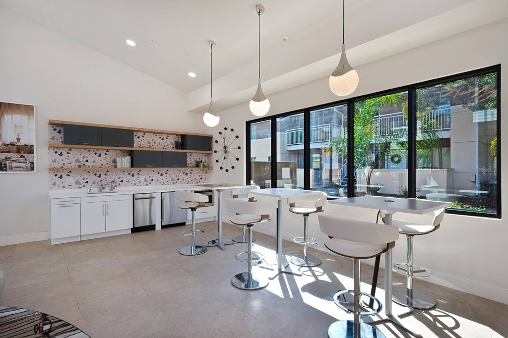 A modern kitchen with white chairs and a bar area.