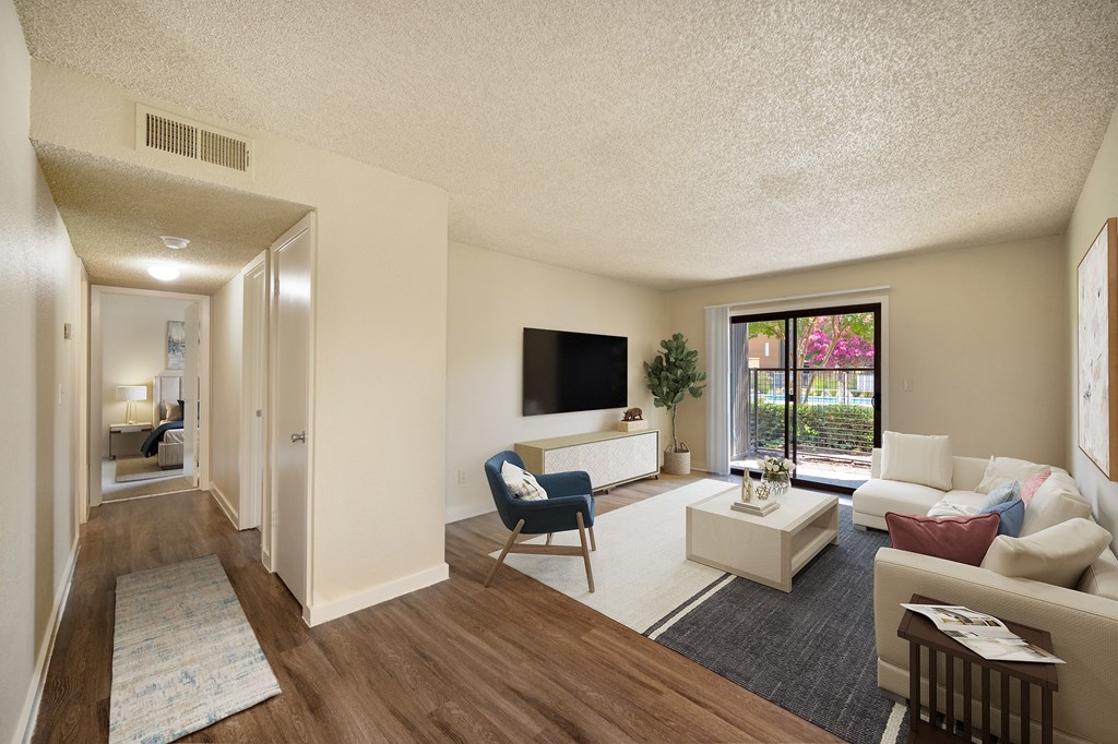 Living room with sectional couch, coffee table, tv on the wall and door to private patio at Fountains of Fair Oaks, California