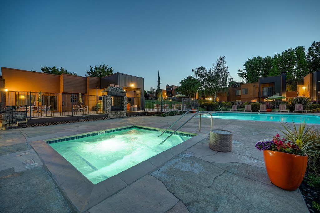 A swimming pool surrounded by a stone patio and a building in the background.