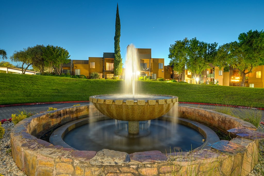 A fountain in the foreground with a building in the background.