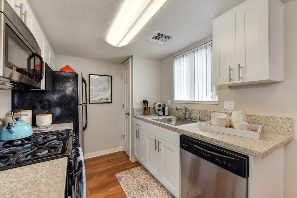 Dining Room/Kitchen with Wood Inspired Floor, Rug, Oven, Stove with Blue Tea Kettle, Microwave at Addison Ranch Apartments, Petaluma, CA, 94954