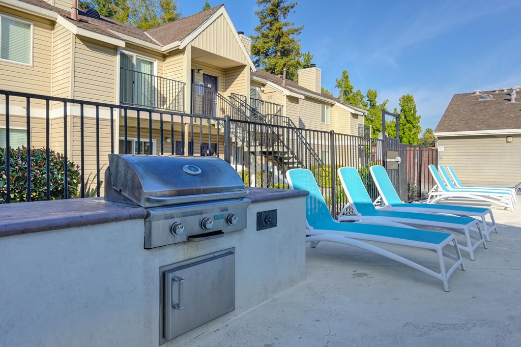 an outdoor patio with chairs and a barbecue grill at Hidden Oaks Apartments, Citrus Heights