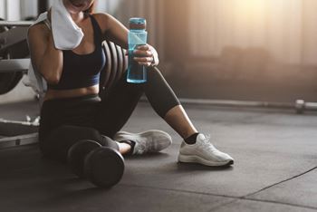 a woman sitting on the floor holding a bottle of water