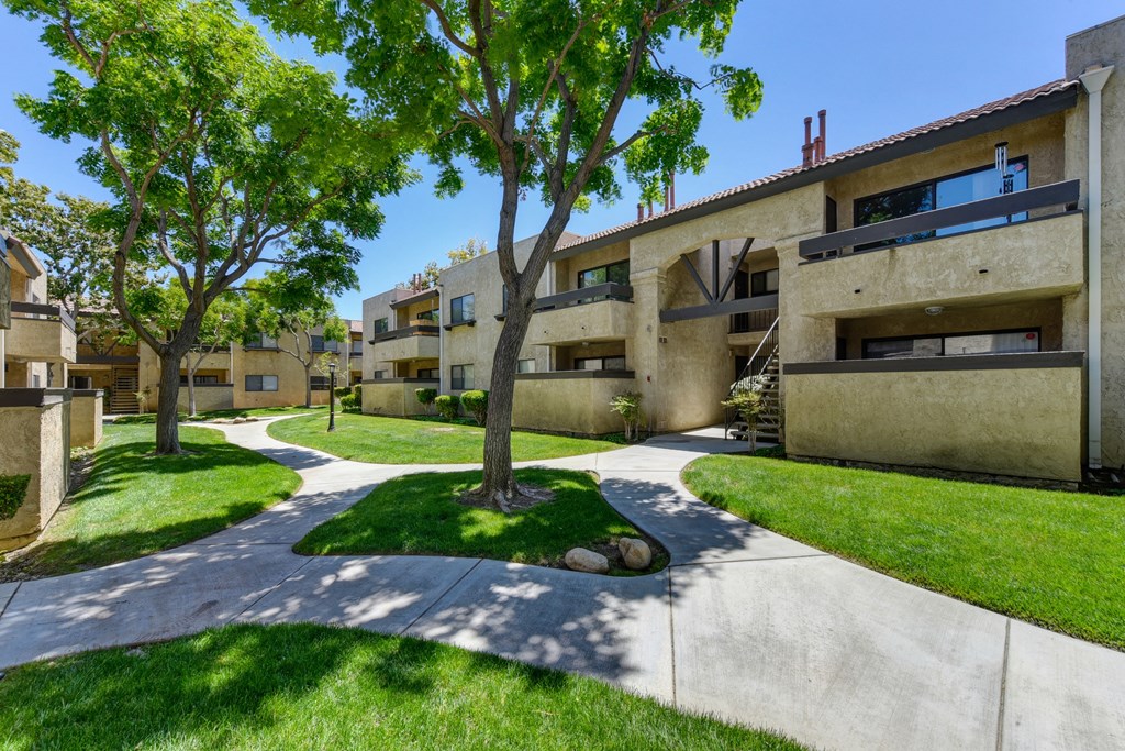 Community Walk Paths with apartment buildings on all sides and mature tress in the center.