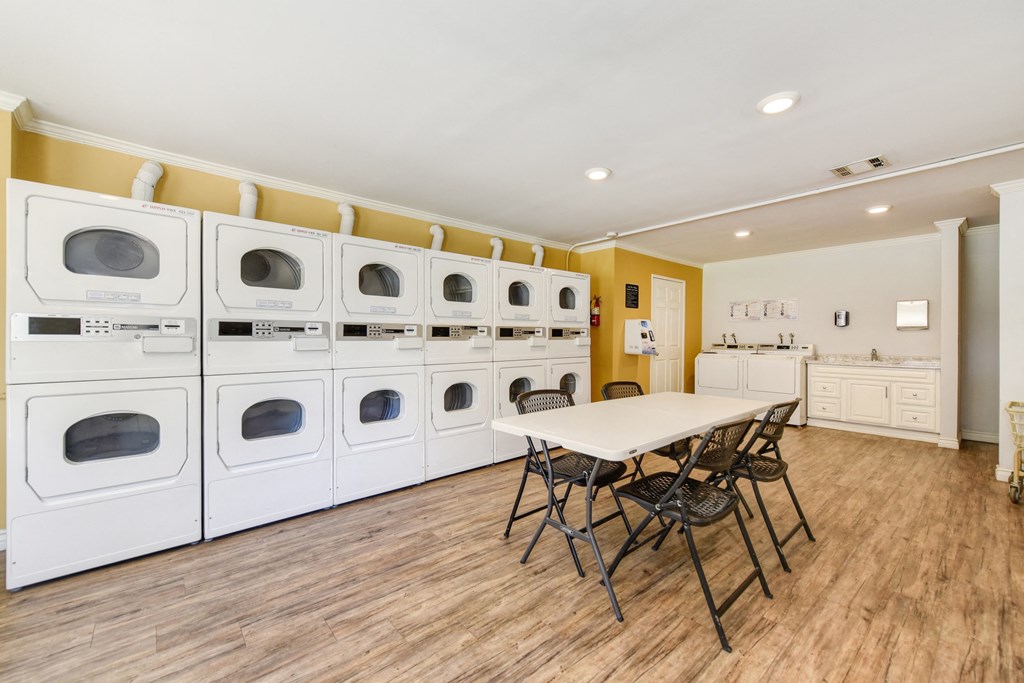 On-Site Laundry Center with multiple laundry machines.  There is a table and chairs in he center of the room.