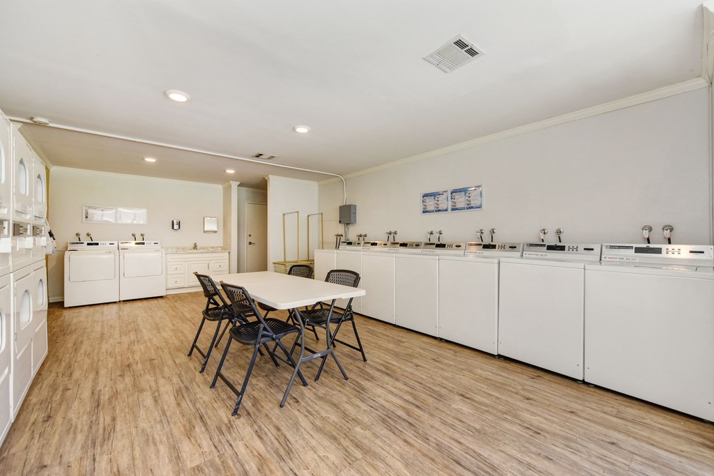 On-Site Laundry Center with multiple laundry machines.  There is a table and chairs in he center of the room.