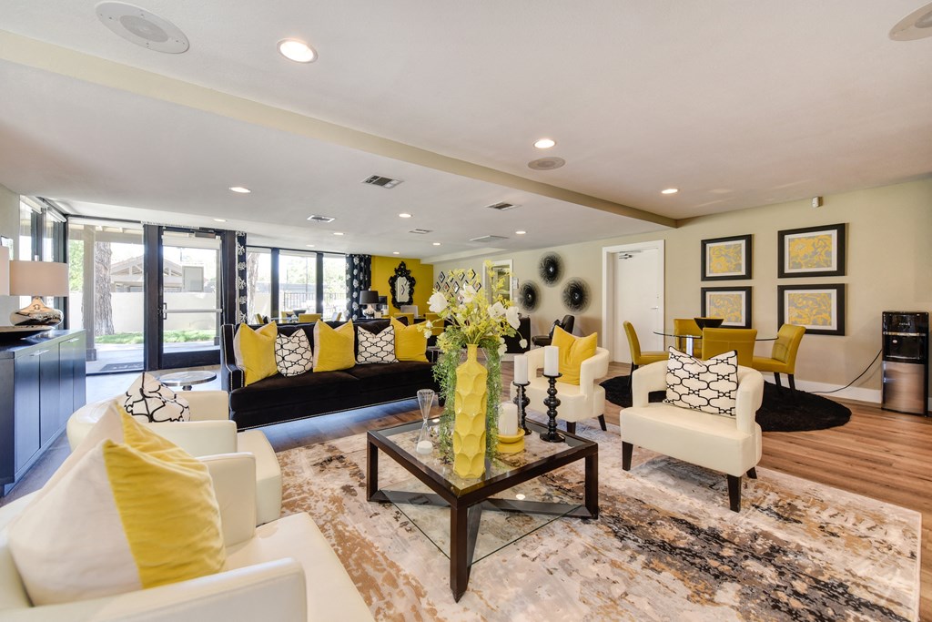 Community leasing office with bright yellow accessories, pillows, and chairs.  There are many seating options and desks.