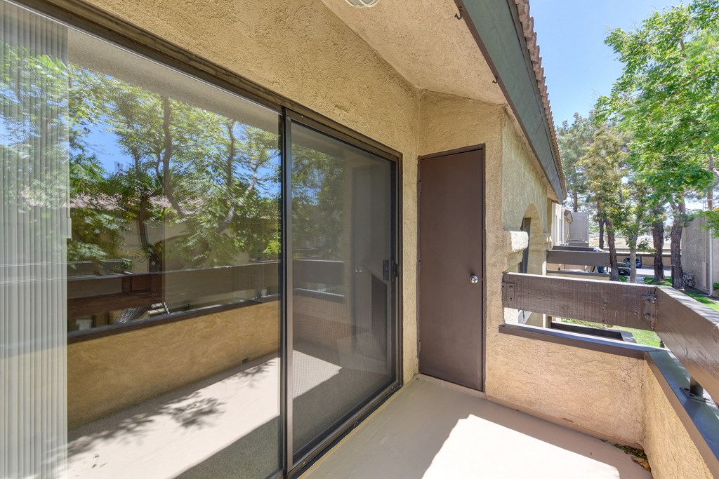 An Apartment balcony with a sliding glass door leading into apartment home.