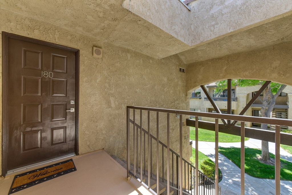 Second floor apartment entrance with staircase leading up to the brown front door