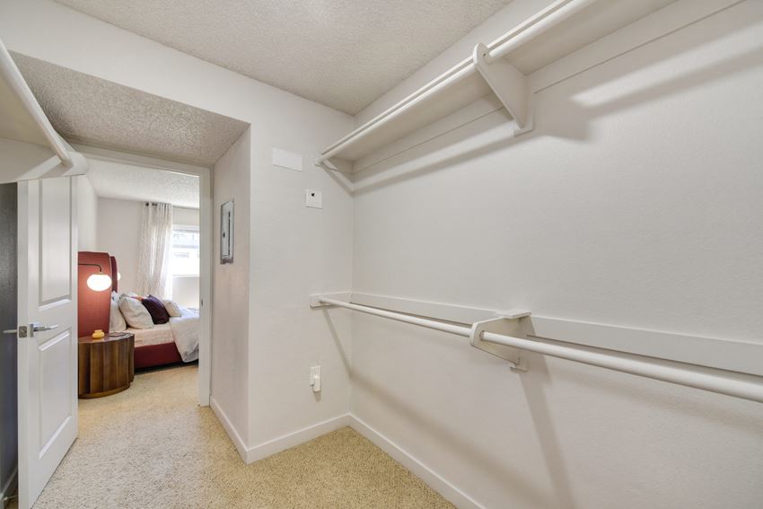Large Extended Closest the entryway to a bedroom with white walls and a door to a hallway with