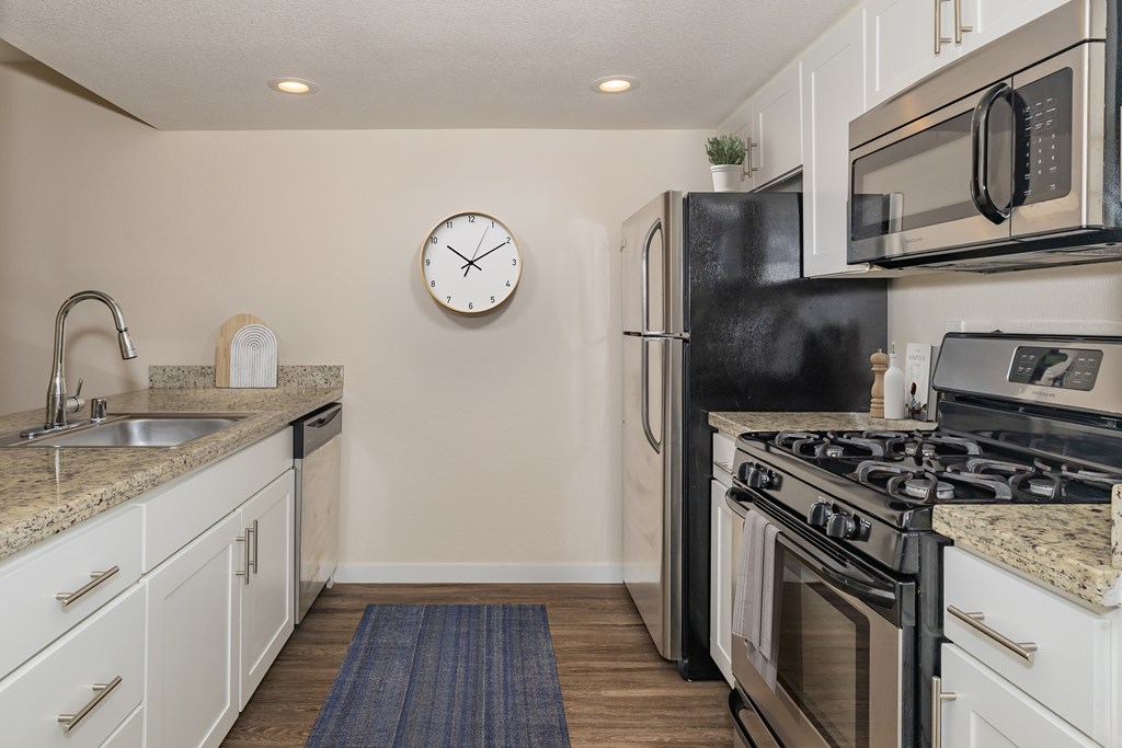 A kitchen with a black refrigerator and stove top oven.