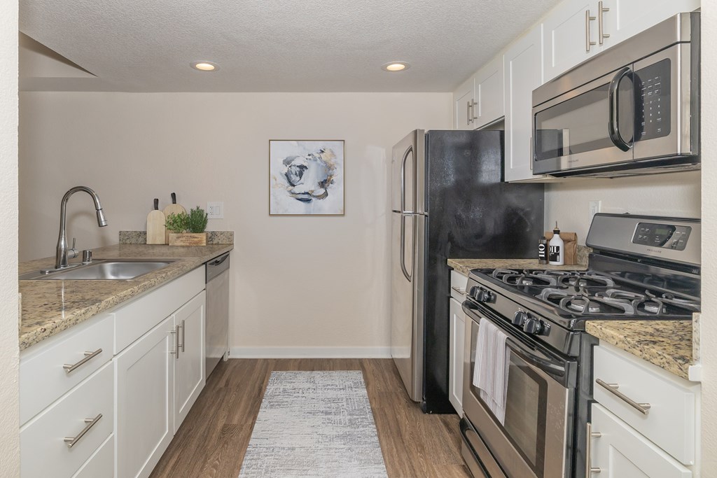 A kitchen with a black refrigerator, stove, and microwave.