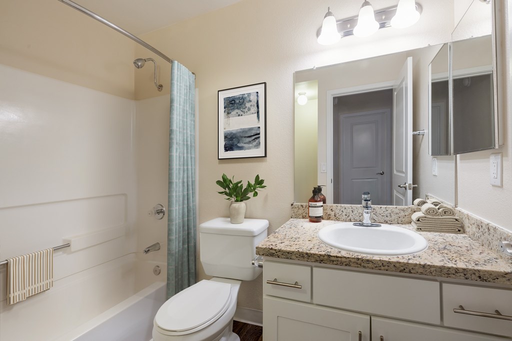 A bathroom with a white toilet, sink, and bathtub.