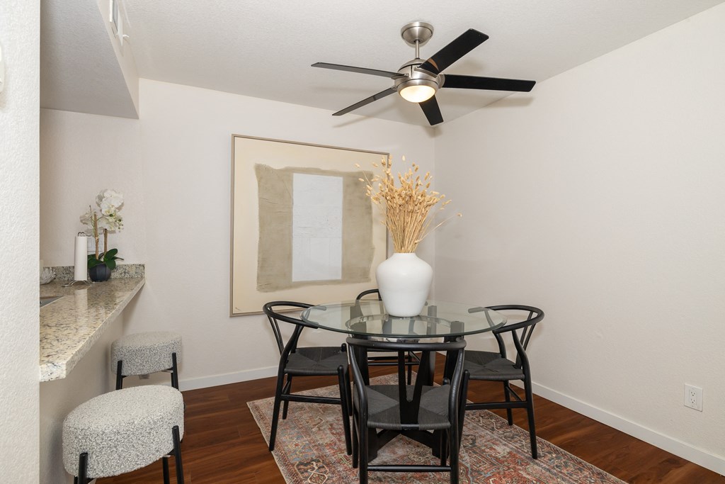 a dining room with a glass table and chairs and a ceiling fan a dining room with a glass table and chairs and a ceiling fan at Rocklin Manor Apartments, Rocklin