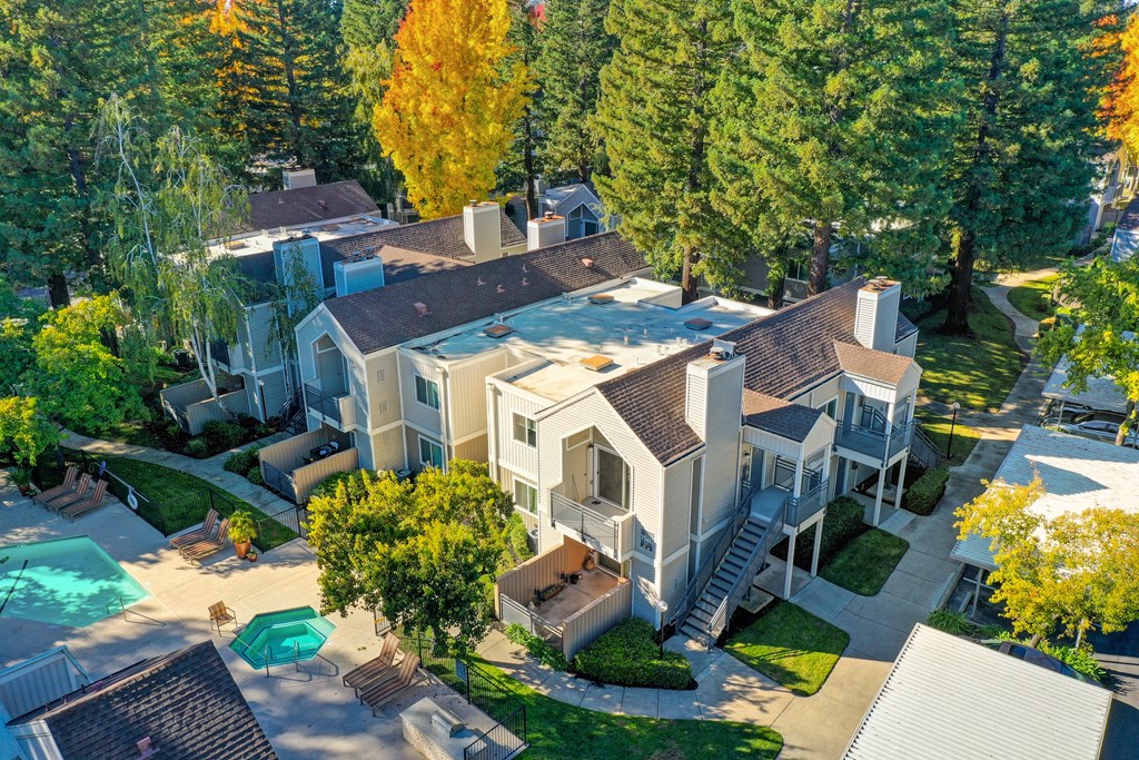Drone image of the property and the neighborhood taken right above the community. Many tress and apartment exterior buildings Drone image of the property and the neighborhood taken right above the community. Many tress and apartment exterior buildings at Rush River Apartments, Sacramento, CA
