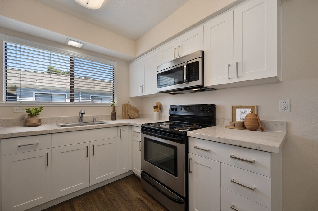a kitchen with white cabinets and black appliances and a window at Silverstone Apartments, Davis