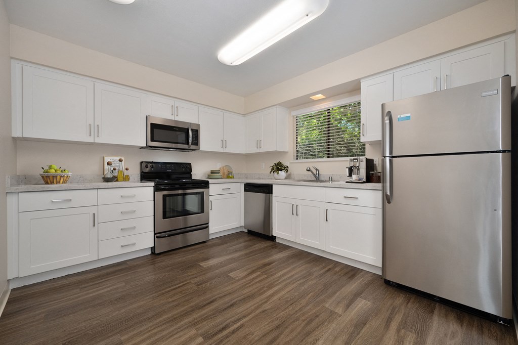 a kitchen with white cabinets and stainless steel appliances in the townhome floorplan at Silverstone Apartments, Davis, CA, 95618