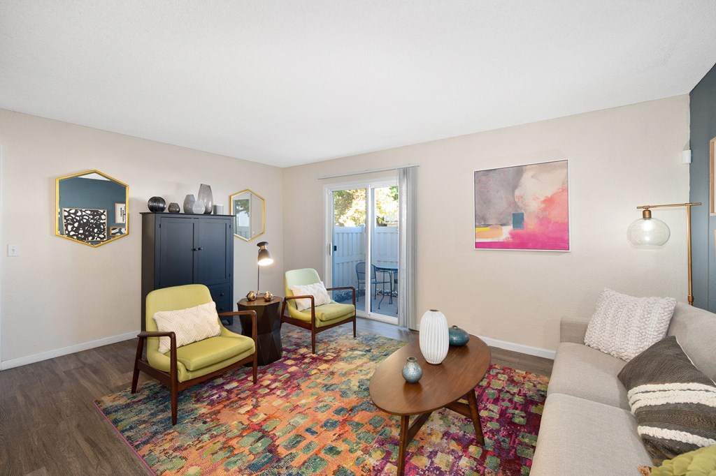 a living room with a couch and chairs and a door to a balcony