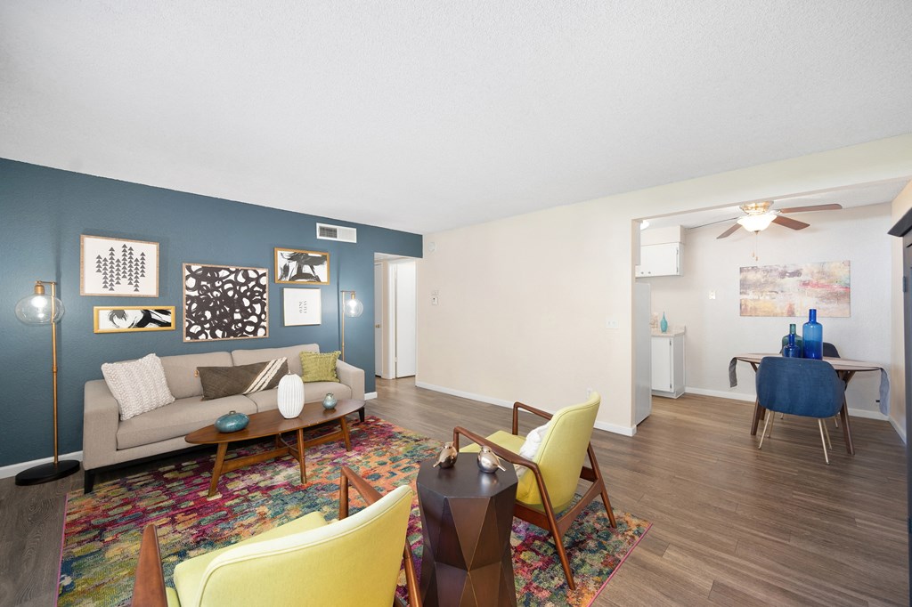 a living room with a couch and chairs and a dining room of in the distance