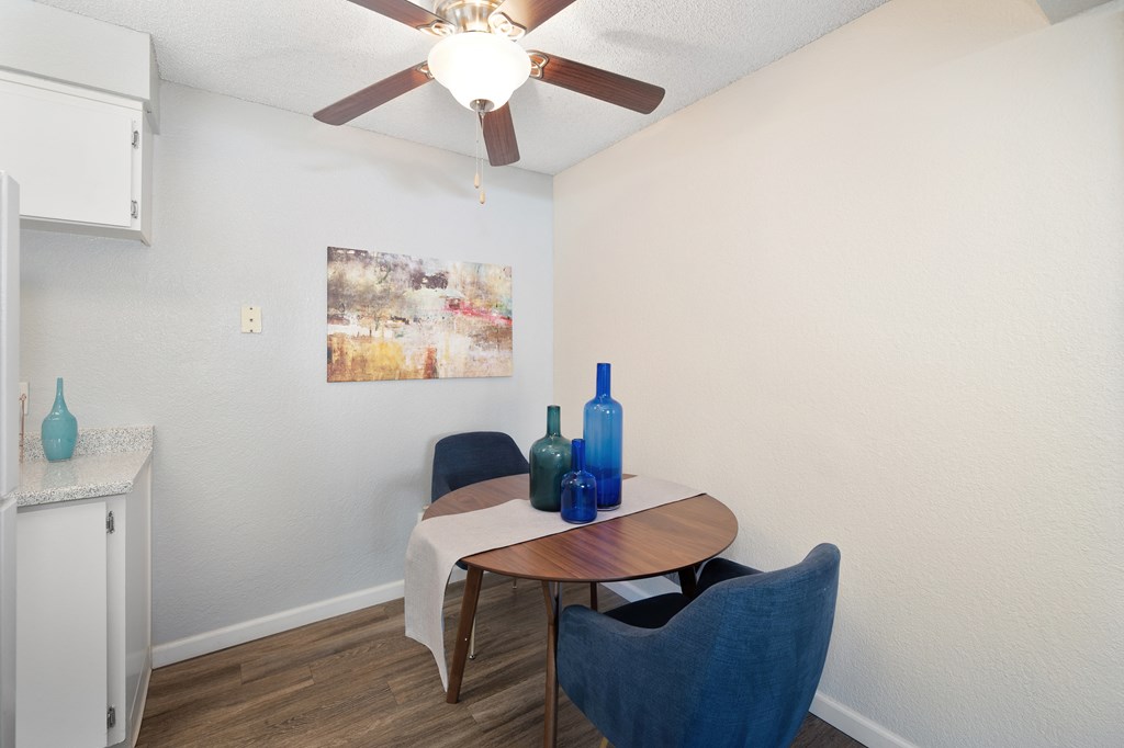 a dining room area with a table and chairs and a ceiling fan