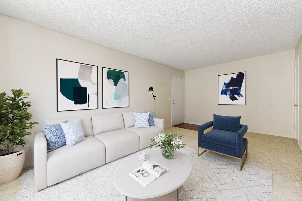 A living room with a white couch, a blue chair, and three framed pictures on the wall.