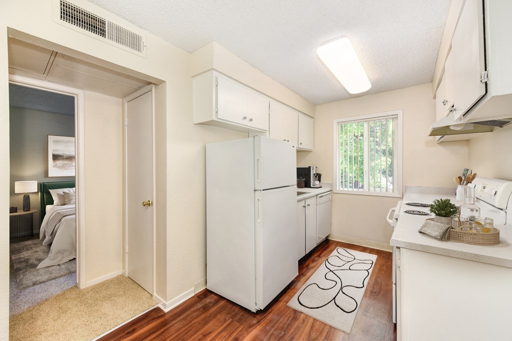 A small white kitchen with a refrigerator, sink, and cabinets.