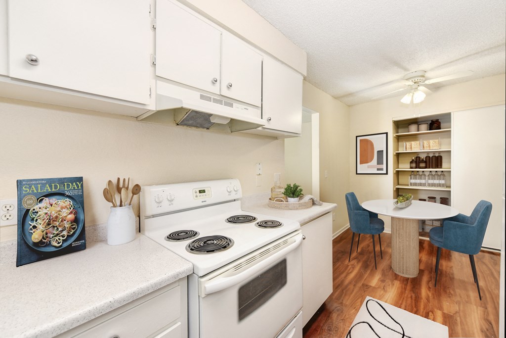 A white kitchen with a stove, oven, and a book titled