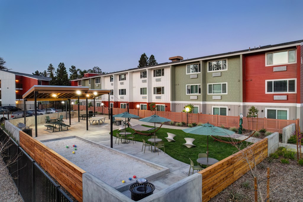 a courtyard with tables and umbrellas in front of an apartment building