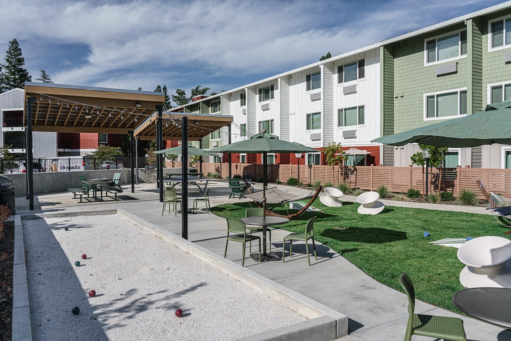 a courtyard with tables and umbrellas in front of an apartment building
