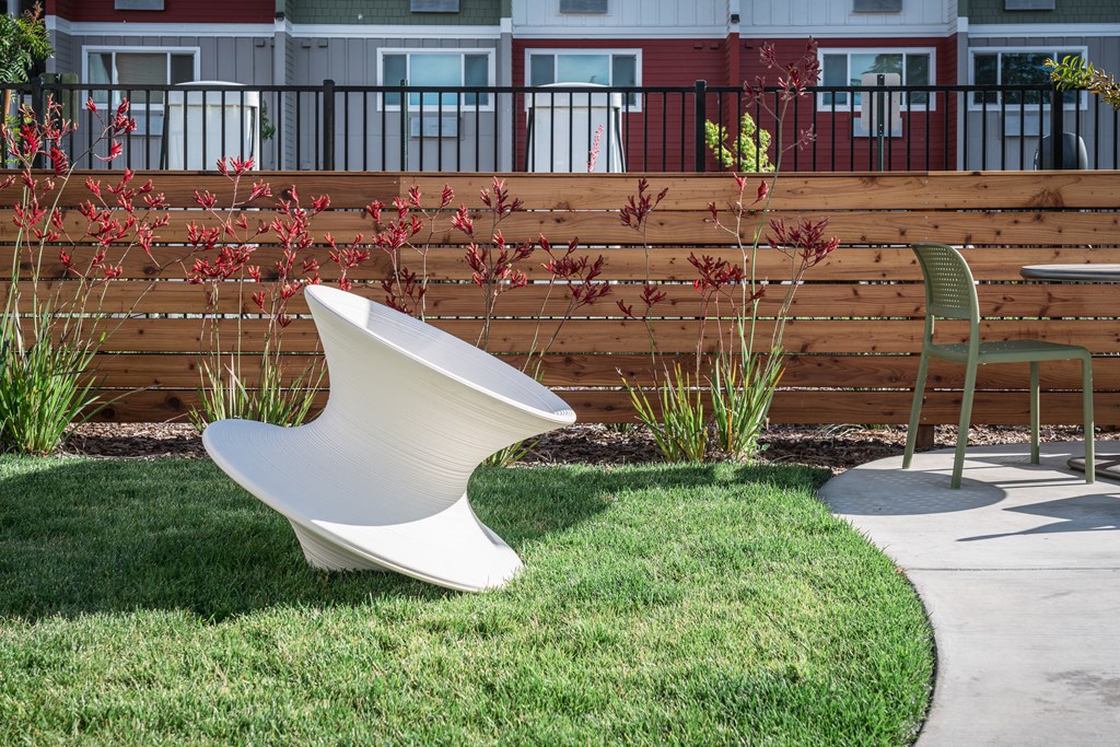 a white urinal sitting in the grass next to a chair