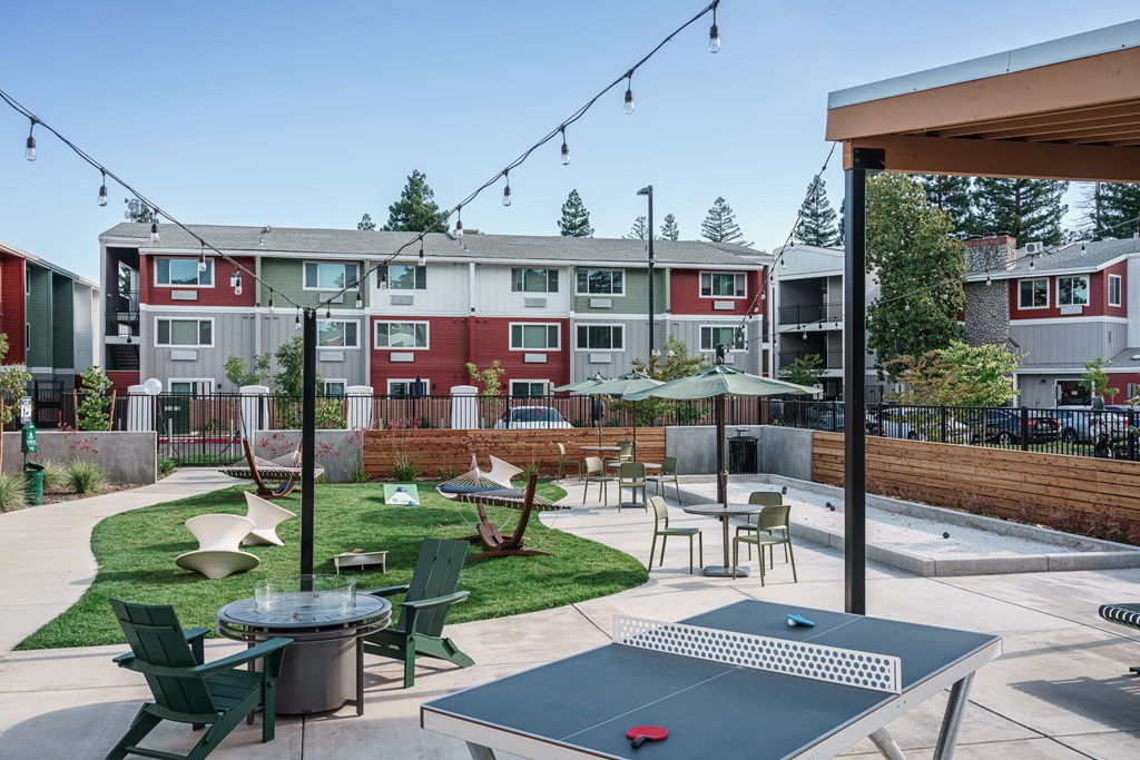 an outdoor patio with tables and chairs and an apartment building in the background