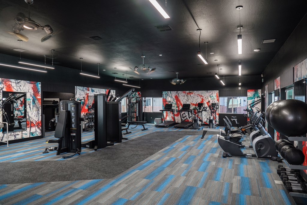 a fitness room with weights and other exercise equipment and a wall of graffiti