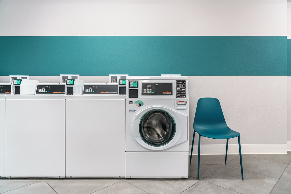 a row of washing machines in a laundry room with a blue chair
