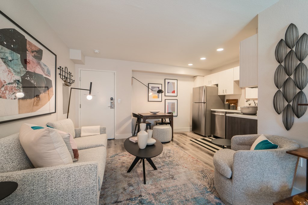 a living room with couches and chairs and a table in front of a kitchen