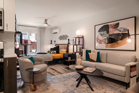 A living room with a grey couch, a round table, and a large abstract painting on the wall.