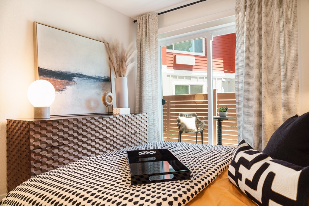 a bedroom with a bed with a black and white comforter and a laptop
