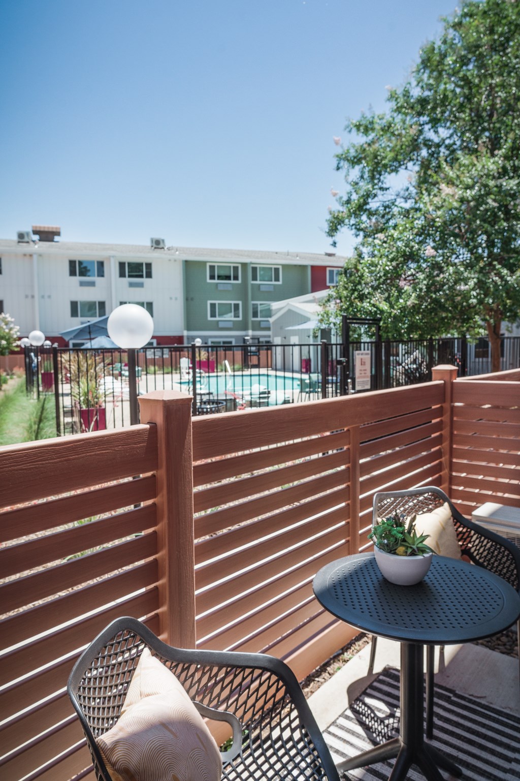 a patio with two chairs and a table on a balcony overlooking the pool area at Track 281 Apartments, Sacramento, 95811