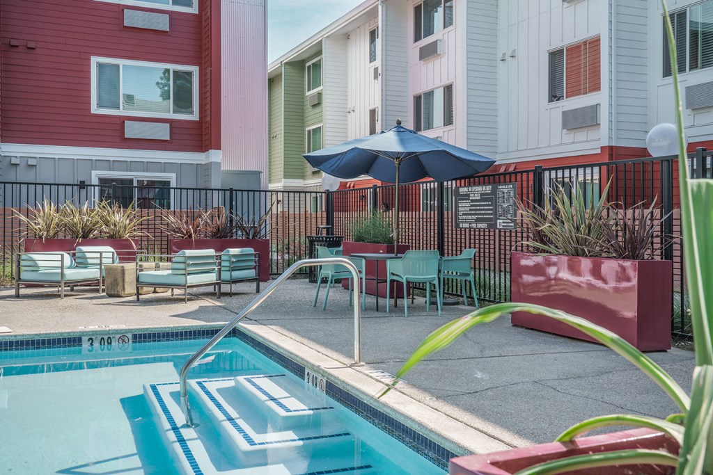 our apartments have a pool and a patio with chairs and an umbrella