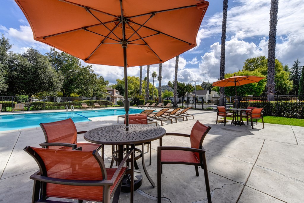 swimming pool area with table, chairs and sun umbrellas at Vineyard Terrace Apartments, California 94558