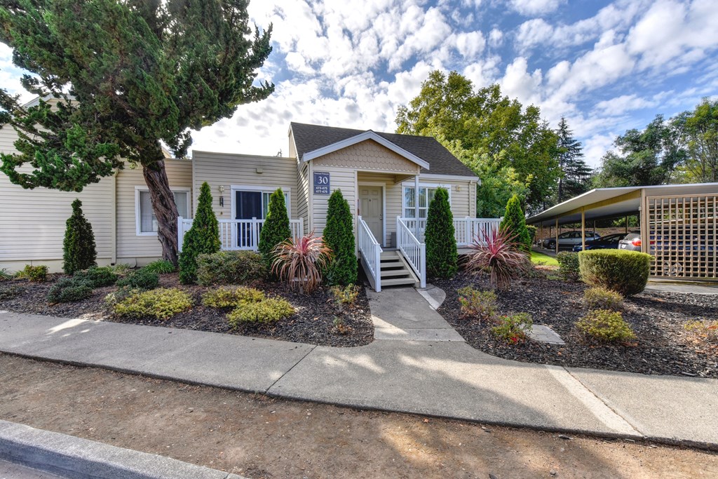 Apartment entrance with small staircase leading up to the front of the building and nice shrubs and tress outside of the building at Vineyard Terrace Apartments, Napa