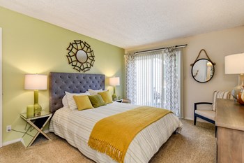 Model home bedroom with queen size bed, carpeting, nightstands and dresser with patio door on one side of room.  - Photo Gallery 9