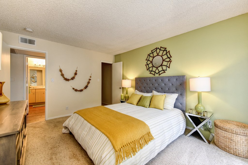 Bedroom with Carpet, light green accent Wall, two nightstands and yellow throw blanket on the bed at Vineyard Terrace Apartments, Napa, CA