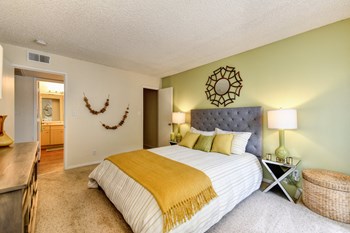 Bedroom with Carpet, light green accent Wall, two nightstands and yellow throw blanket on the bed. - Photo Gallery 10