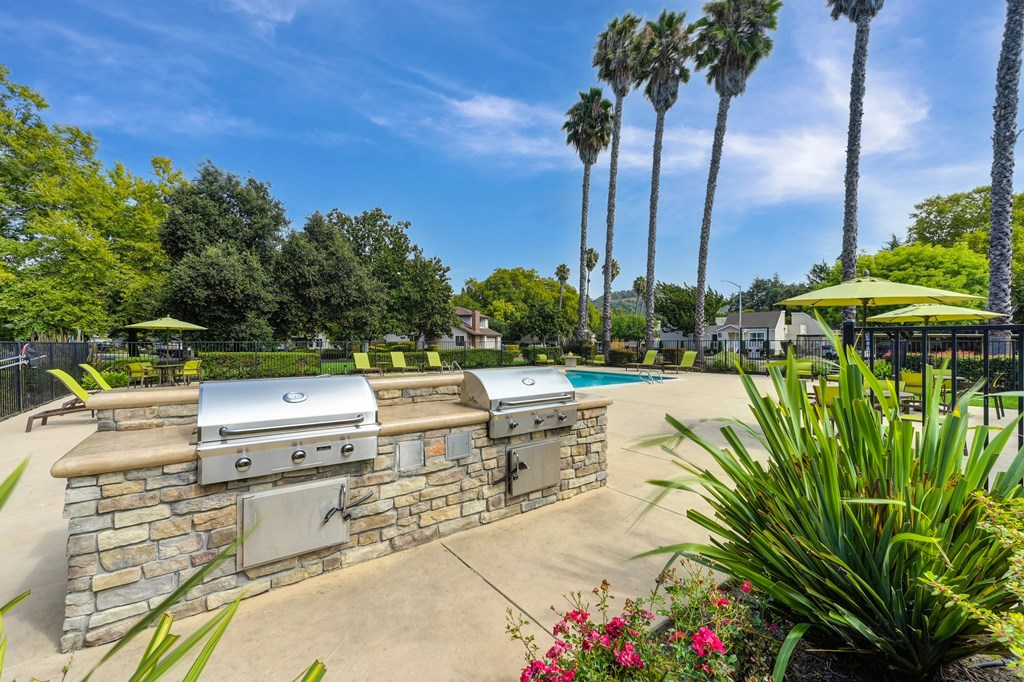 A backyard with a stone wall and a grill.
