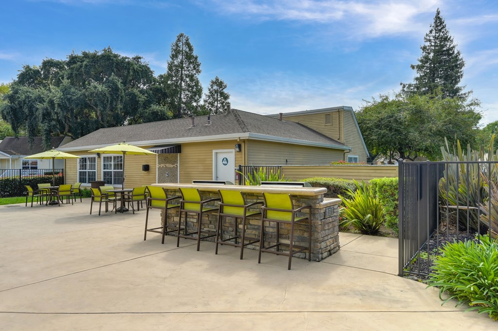 A yellow and brown building with a patio and chairs.
